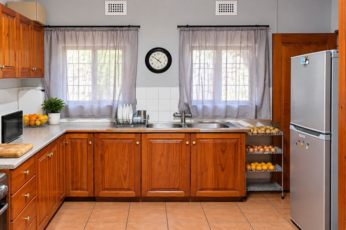 A functional kitchen featuring warm timber cabinetry, laminate countertops, a gas cooktop, and tiled flooring, offering a classic and practical workspace.