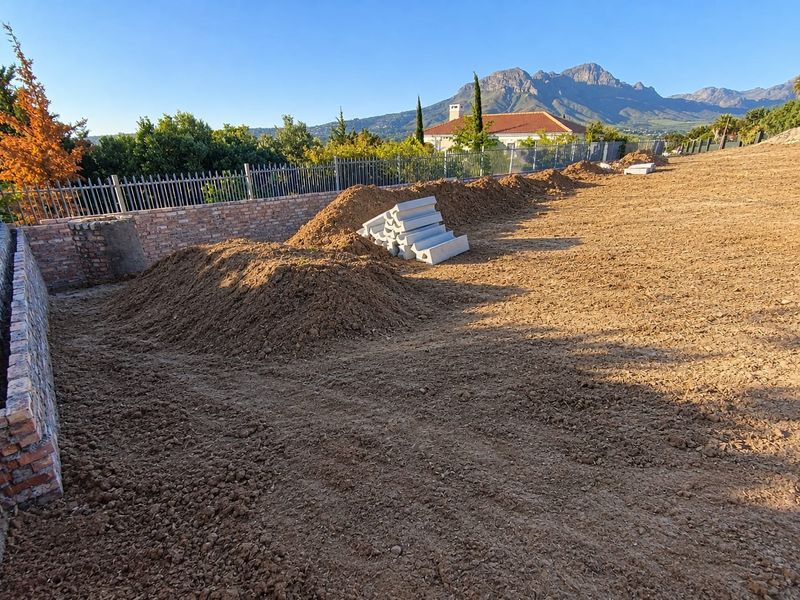 Vacant residential land featuring a brick retaining wall, metal fencing, and mountain views, currently undergoing site preparation.