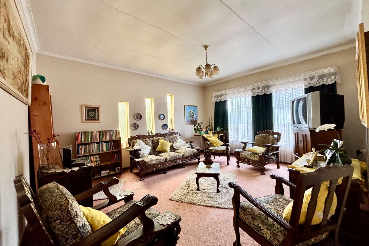 A traditional living room featuring vertical slit windows and a central ceiling light fixture, offering a classic layout with potential for modern updates.