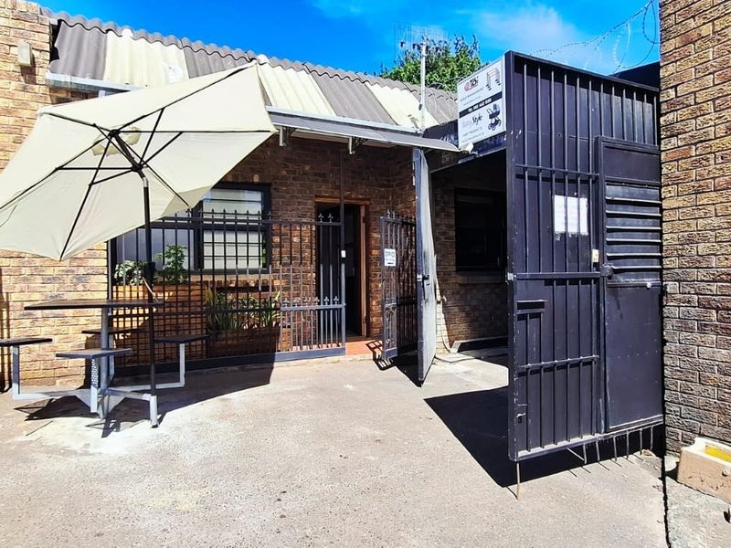 Industrial property entrance featuring a face brick facade, secure metal gates, and paved outdoor area.