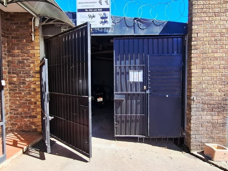 Industrial property entrance featuring a brick facade, metal security gates, and razor wire fencing for enhanced security.