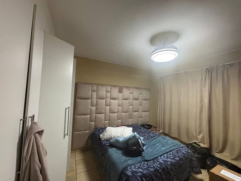A bedroom featuring tiled flooring, a built-in wardrobe, and a central ceiling light fixture.