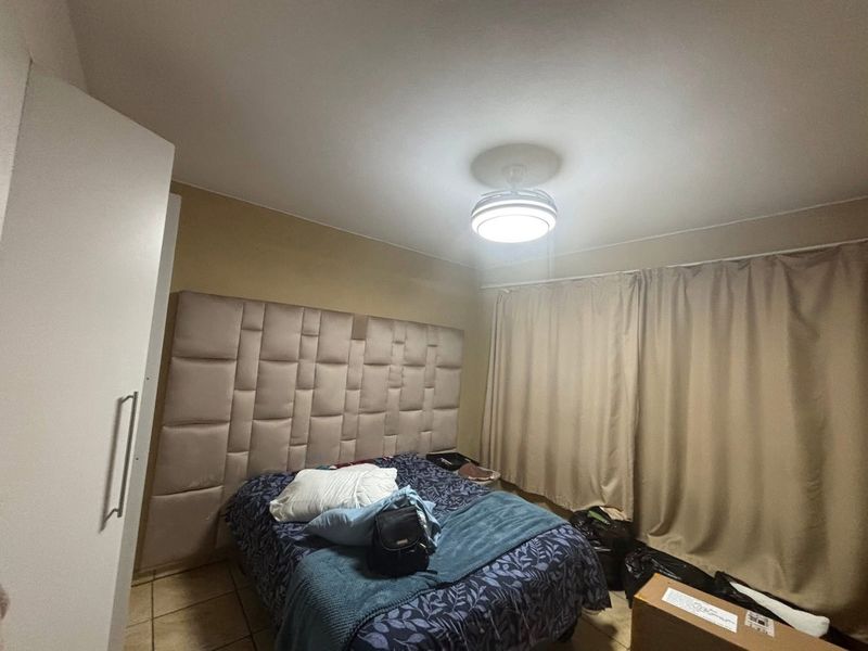 A bedroom featuring tiled flooring, a built-in wardrobe, and a central ceiling light fixture.