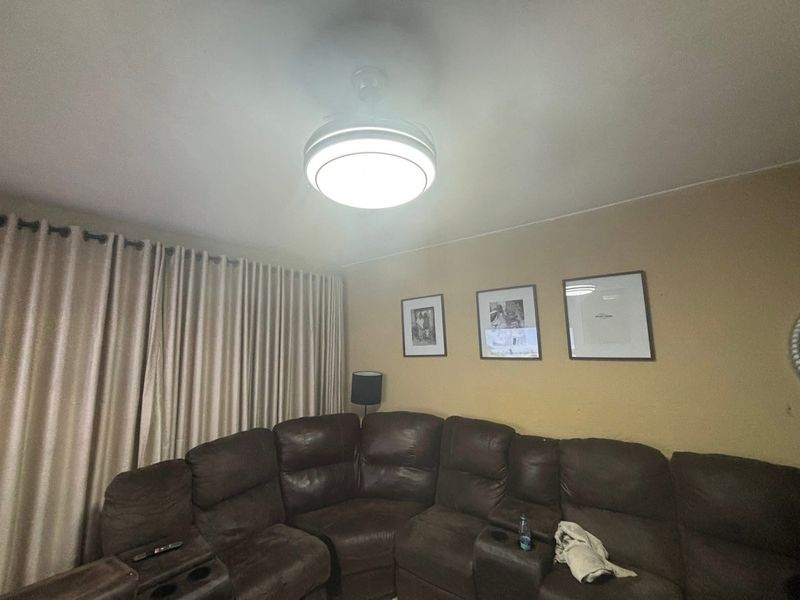 A living room area featuring a ceiling fan and floor-to-ceiling curtain tracks.