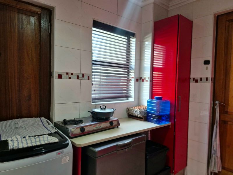 A functional kitchen area featuring tiled walls, built-in cabinetry, and a gas hob, providing a practical space for cooking and food preparation.