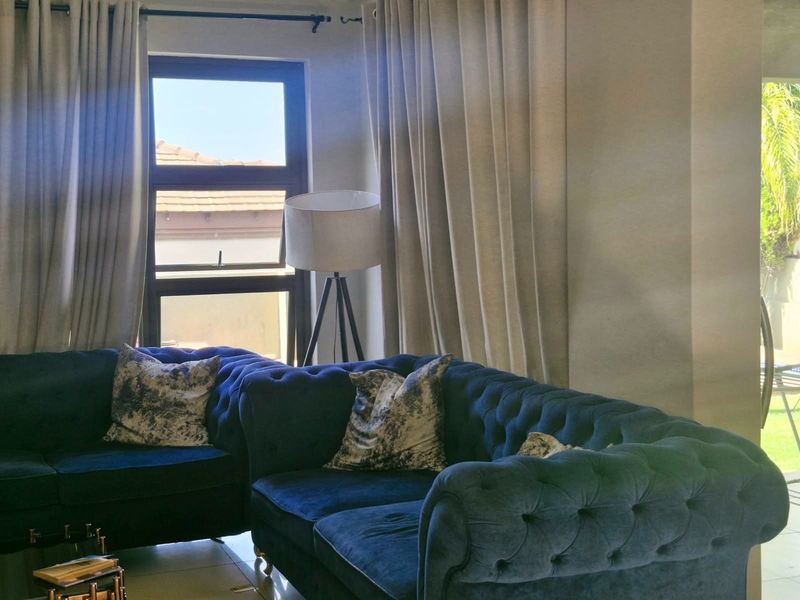 A bright living room area featuring tiled flooring and a large window that allows for natural light.