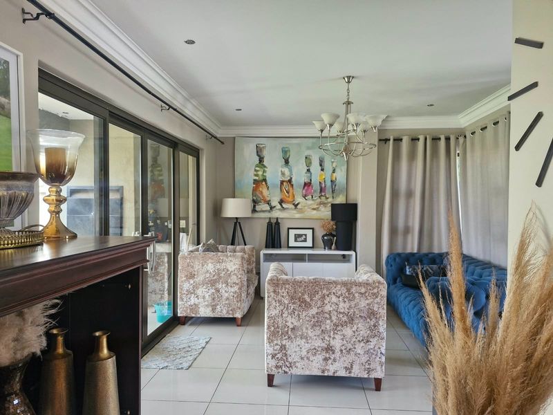 A well-lit living room featuring large sliding glass doors, tiled flooring, and elegant crown molding, creating a bright and inviting space.