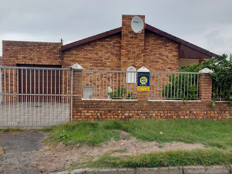 Front elevation of a face brick apartment featuring a secure perimeter wall, metal fencing, and an integrated garage with a roller door.