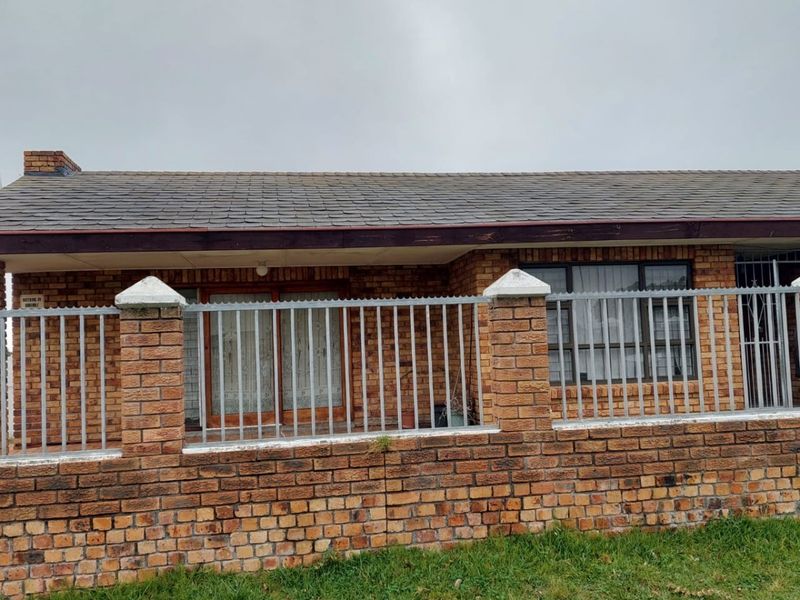 Front exterior view of a single-story face brick apartment featuring a tiled roof and secure perimeter fencing with a brick boundary wall.