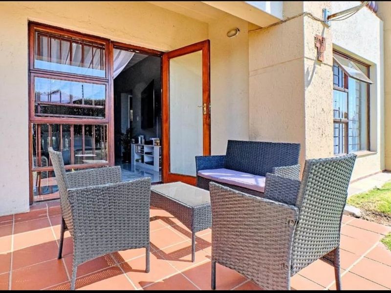 A ground floor patio area featuring terracotta tiling and wooden framed glass doors leading into the apartment interior.