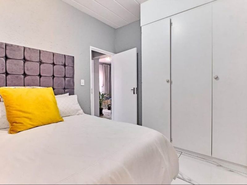 A well-maintained bedroom featuring built-in cupboards, tiled flooring, and a classic tongue and groove ceiling design.