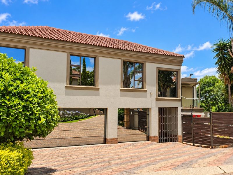 A well-maintained double-storey residence featuring a paved driveway, double garage, and secure gated entrance with modern aluminium window frames.