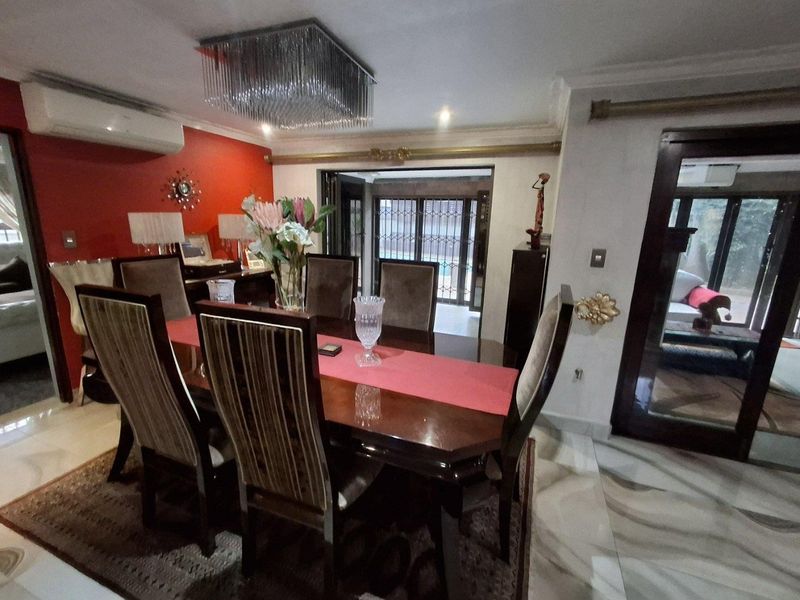 A formal dining room featuring tiled flooring, a decorative crystal chandelier, and direct access to an outdoor area through sliding glass doors.