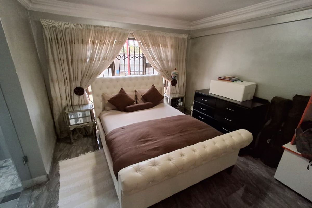 A well-maintained bedroom featuring crown molding, tiled flooring, and a window fitted with a security gate.