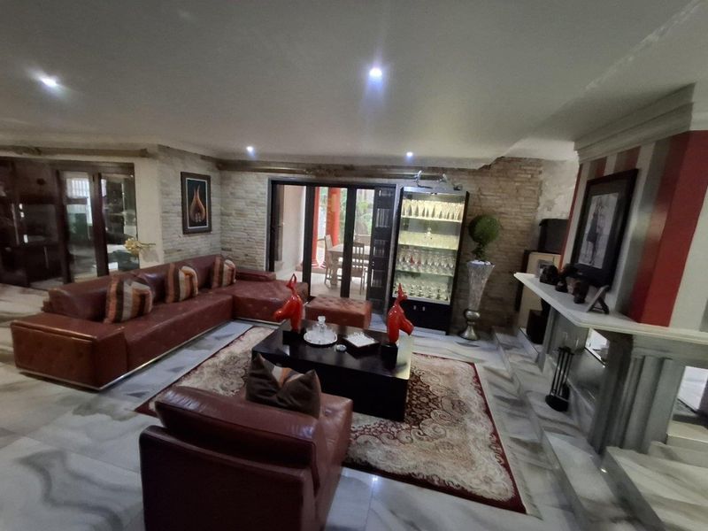 Spacious living room featuring marble flooring, a stone accent wall, recessed lighting, and a fireplace mantel, with direct access to the patio.