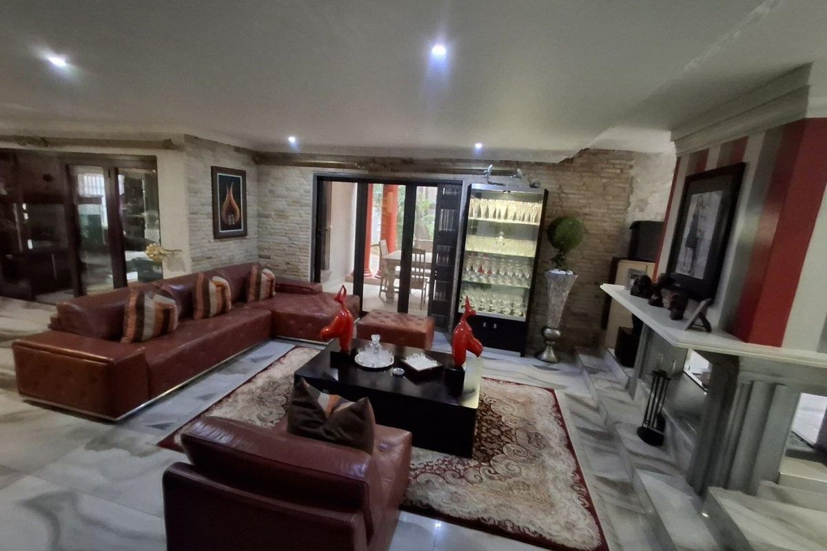 Spacious living room featuring marble flooring, a stone accent wall, recessed lighting, and a fireplace mantel, with direct access to the patio.