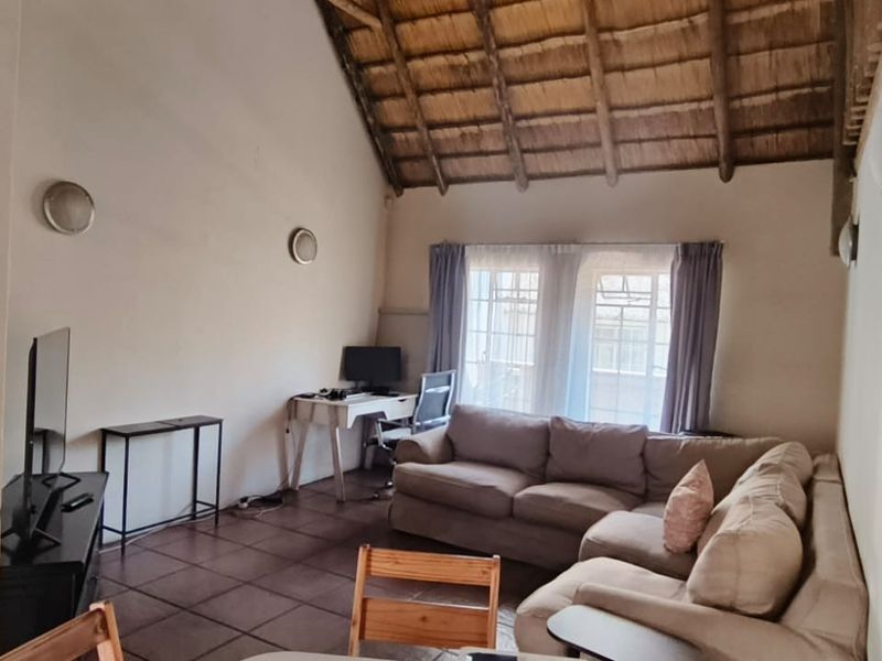 Spacious living area featuring a high vaulted thatched ceiling with exposed timber rafters and tiled flooring, offering a rustic and airy atmosphere.