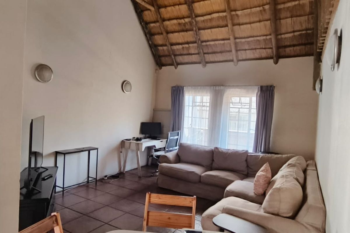 Spacious living area featuring a high vaulted thatched ceiling with exposed timber rafters and tiled flooring, offering a rustic and airy atmosphere.