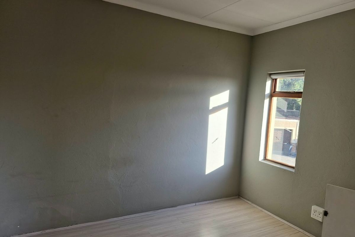 An empty bedroom featuring laminate flooring, a timber-framed window, and neutral wall finishes, offering a blank canvas for personalization.