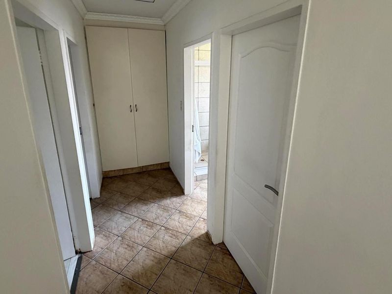 A functional hallway featuring tiled flooring, built-in storage cupboards, and access to adjacent rooms.