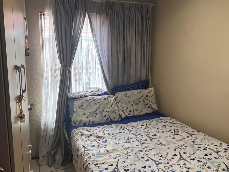 A compact bedroom featuring tiled flooring and a built-in wardrobe, offering a functional space with natural light from the window.