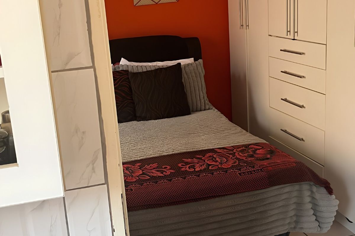 A compact bedroom featuring built-in wardrobes and tiled flooring, offering functional storage space.