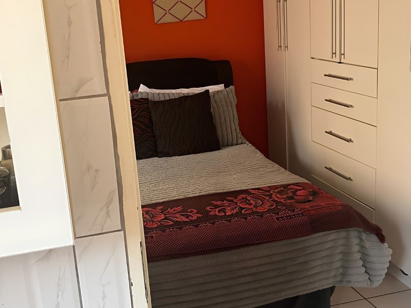 A compact bedroom featuring built-in wardrobes and tiled flooring, offering functional storage space.
