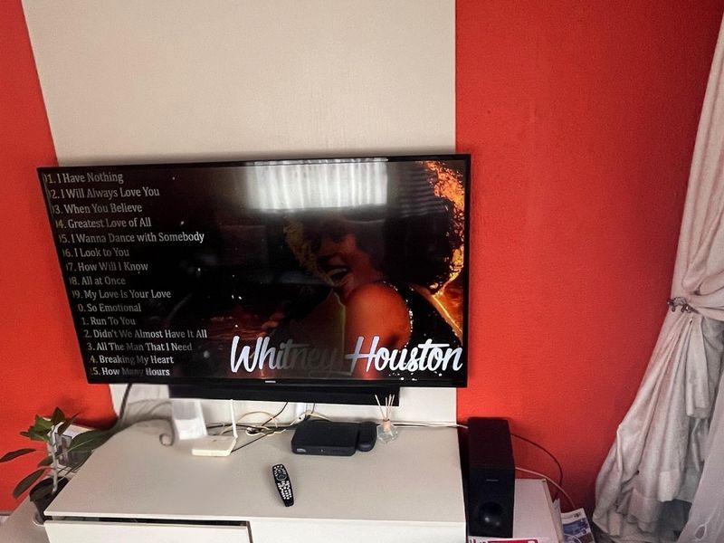 A living room area featuring a wall-mounted television against a red and white accent wall.