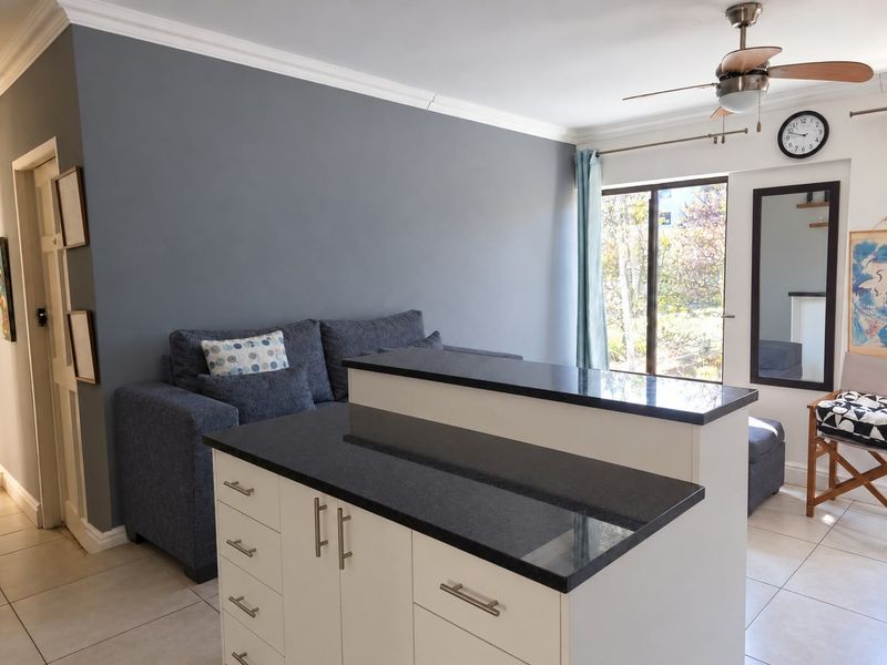 Open plan living area featuring a kitchen island with granite countertops, tiled flooring, and access to an outdoor space through sliding glass doors.