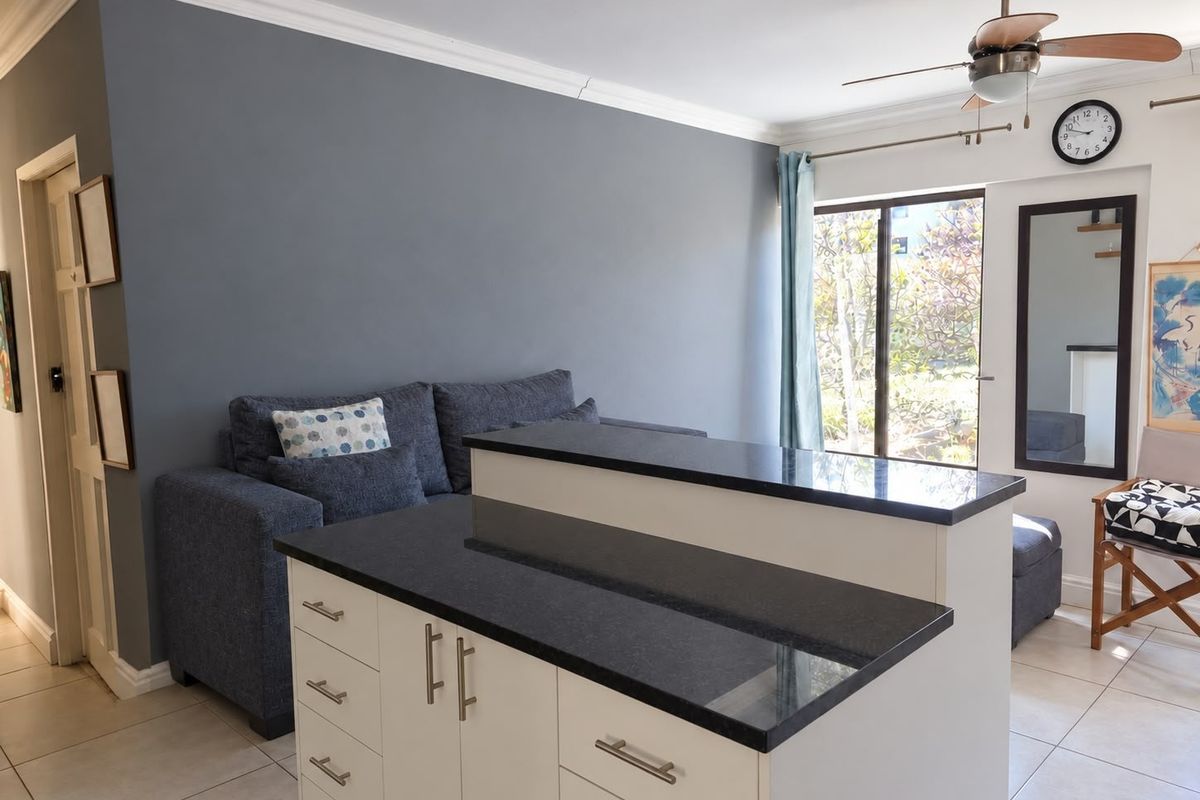 Open plan living area featuring a kitchen island with granite countertops, tiled flooring, and access to an outdoor space through sliding glass doors.
