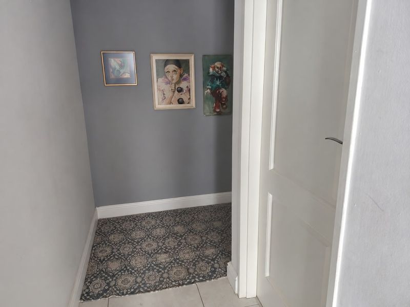A neutral hallway space featuring grey painted walls, patterned floor tiling, and a white internal door.
