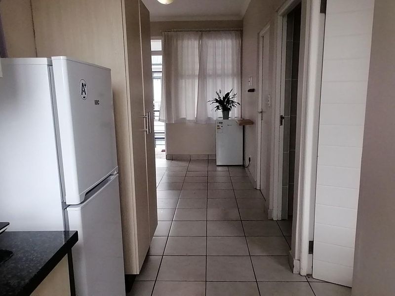 A functional hallway featuring tiled flooring and built-in cabinetry, providing access to other areas of the apartment.