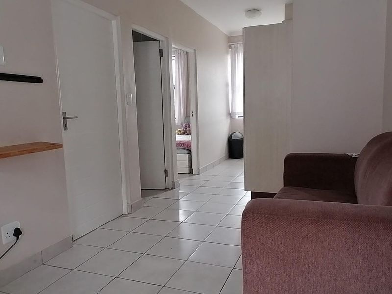 A functional hallway featuring tiled flooring and access to adjacent rooms, providing a clean and neutral transition space within the apartment.