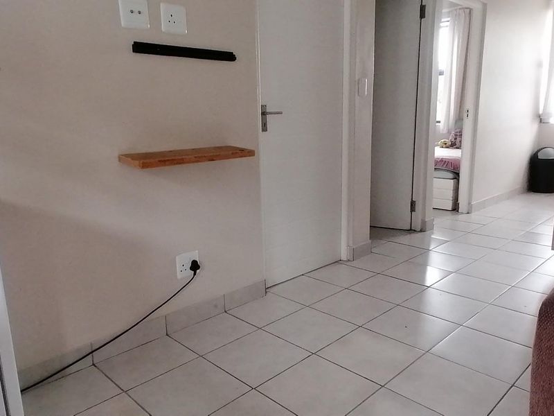 A tiled hallway connecting multiple rooms within the apartment, featuring neutral wall finishes and standard internal door access.