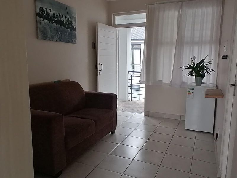 A compact living area featuring tiled flooring, a built-in cupboard, and direct access to an outdoor balcony area.