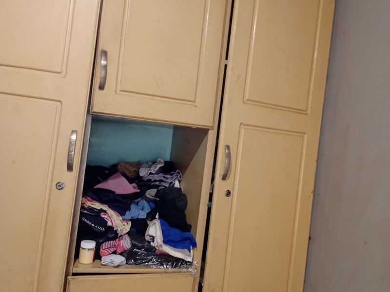A bedroom featuring a built-in wardrobe with multiple storage compartments and cabinet doors.