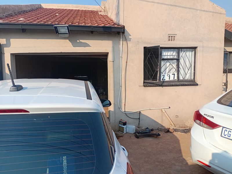 Front elevation of a residential property featuring a garage entrance, security-barred window, and tiled roof structure.