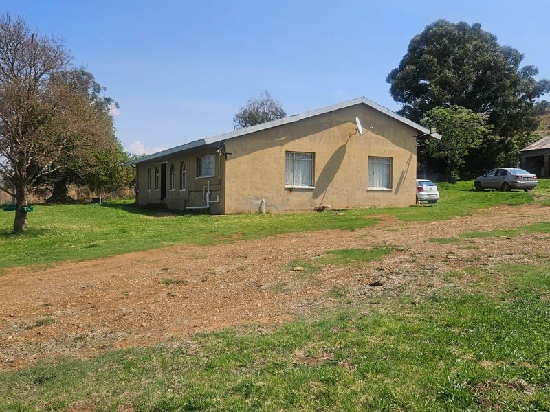 A view of the rear exterior of a farm dwelling featuring plastered walls, a pitched roof, and surrounding open land.