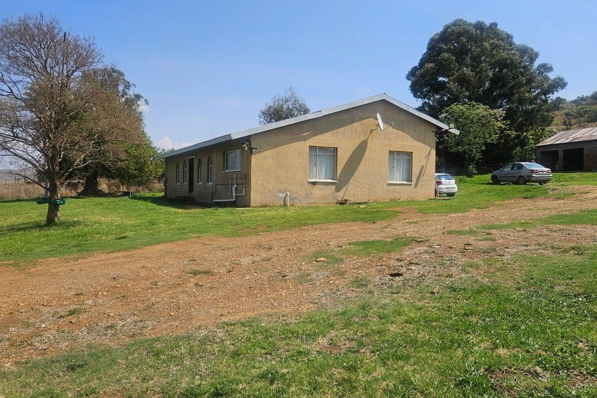 A view of the rear exterior of a farm dwelling featuring plastered walls, a pitched roof, and surrounding open land.