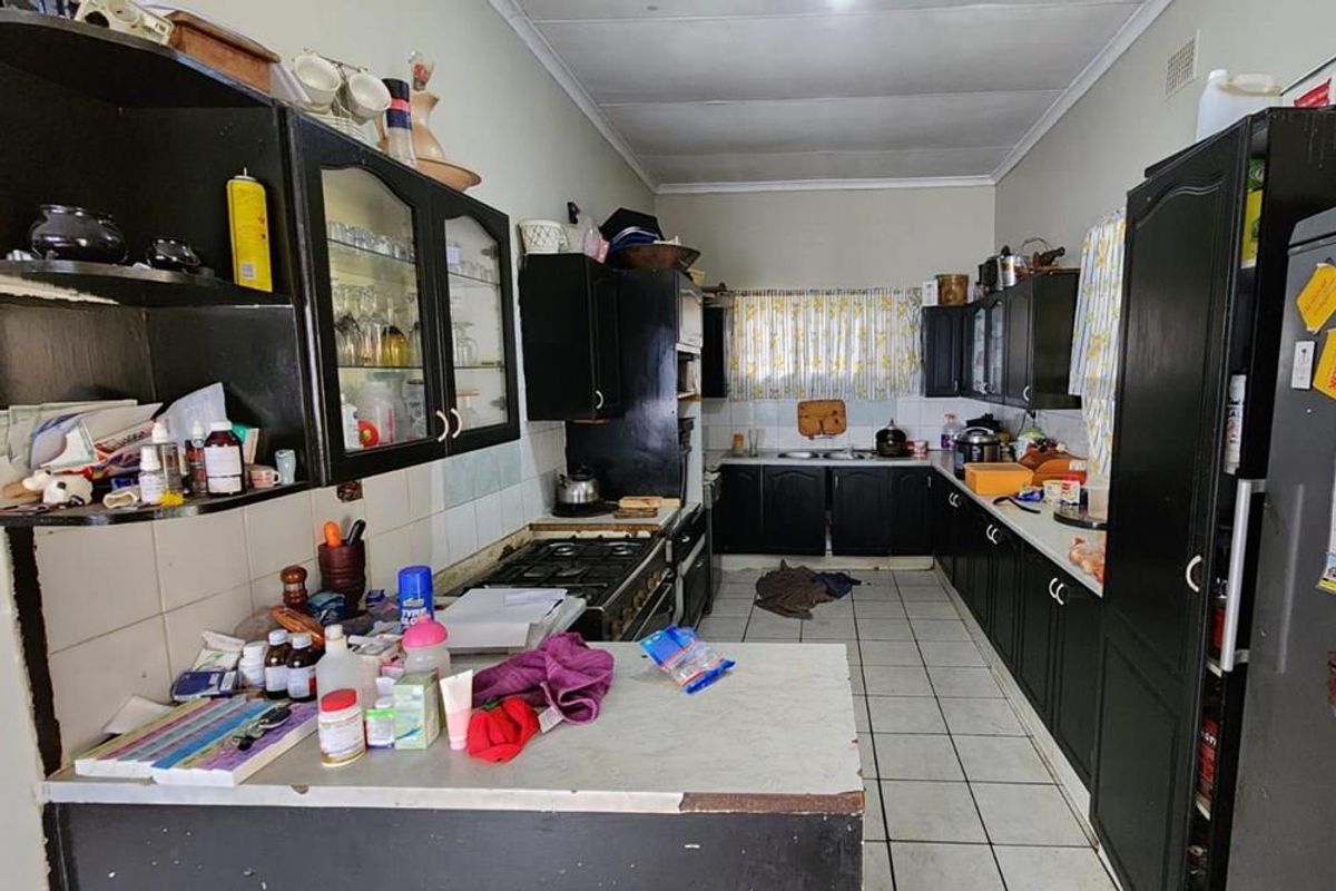 A functional kitchen featuring dark built-in cabinetry, a gas stove, and tiled flooring, offering potential for a modern renovation.