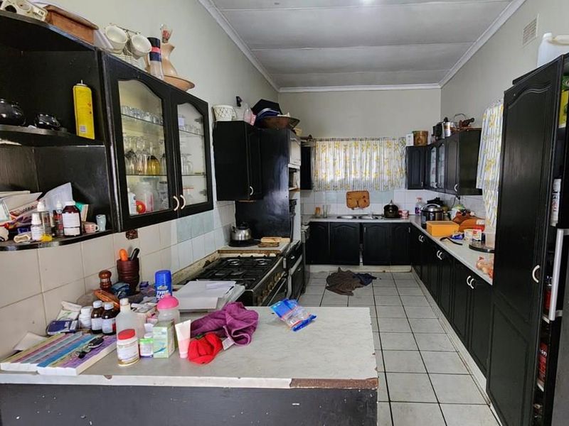 A functional kitchen featuring dark built-in cabinetry, a gas stove, and tiled flooring, offering potential for a modern renovation.