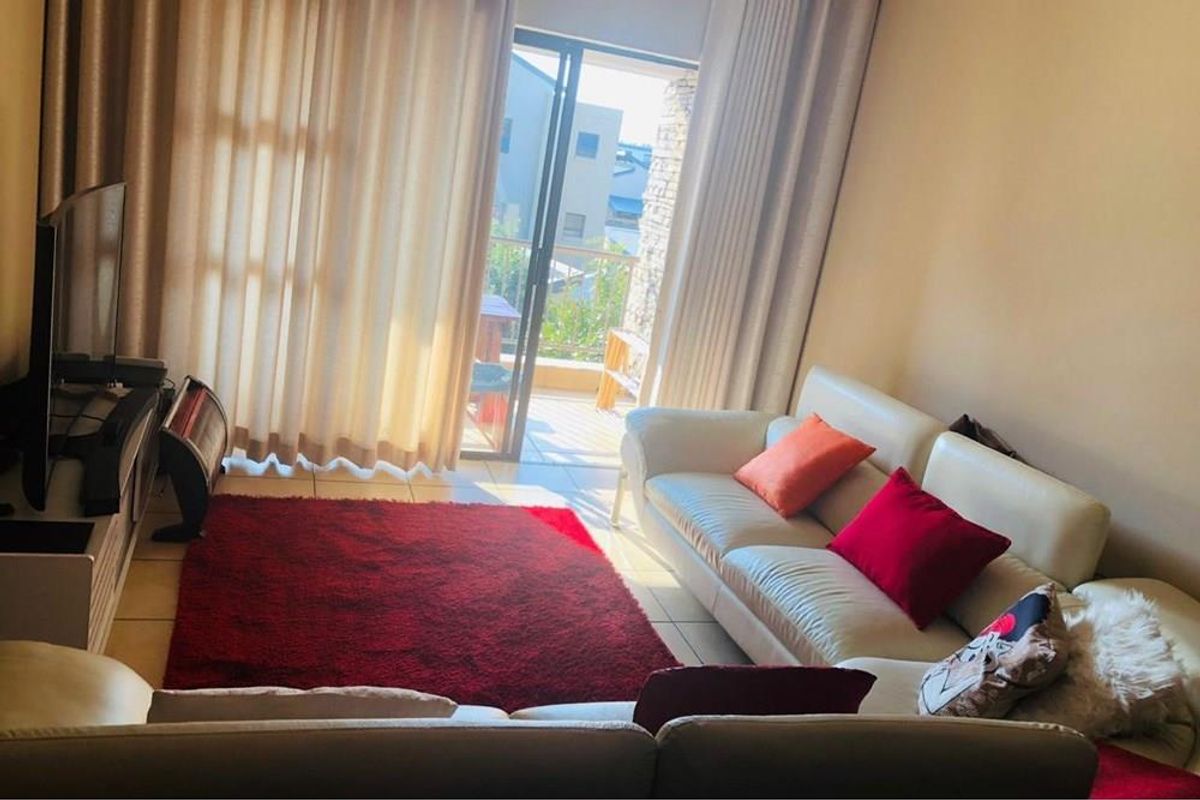 A comfortable living room featuring tiled flooring and large sliding glass doors that provide access to an outdoor balcony area.