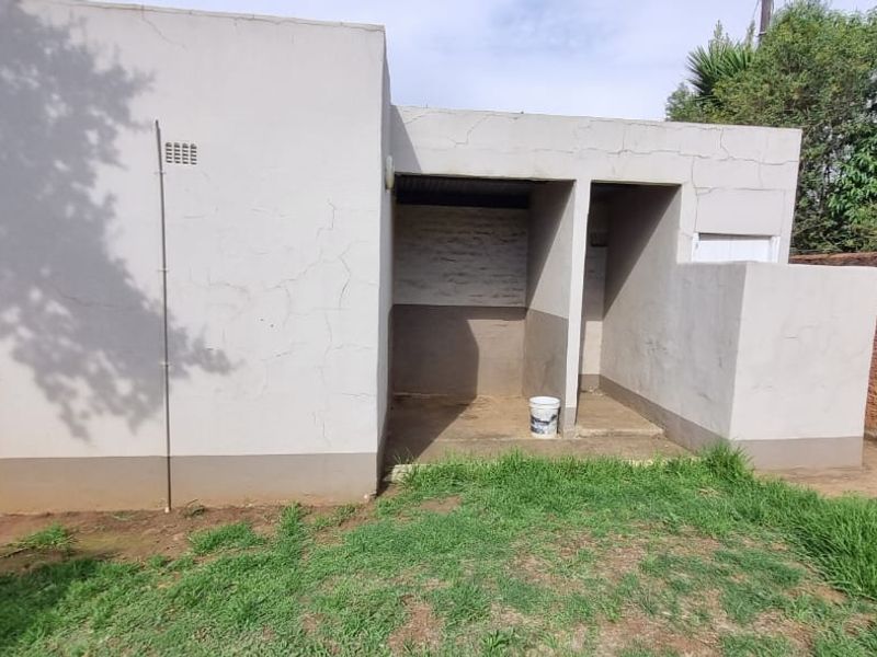A detached utility structure featuring two open-access bays, suitable for storage or laundry use, located in the rear garden area.