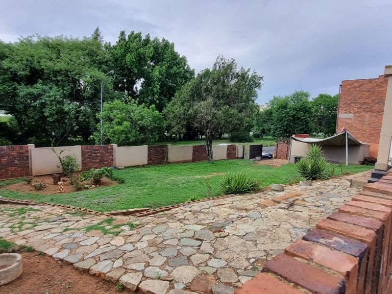 A spacious rear garden featuring a stone-paved patio area, established lawn, and perimeter brick walling, offering a private outdoor space.