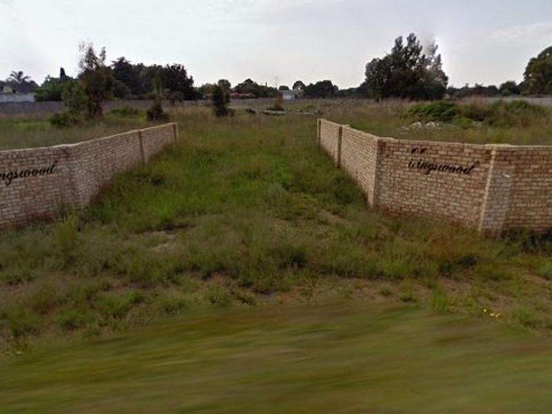 Vacant residential land featuring brick boundary walls at the entrance, situated in a quiet estate setting.