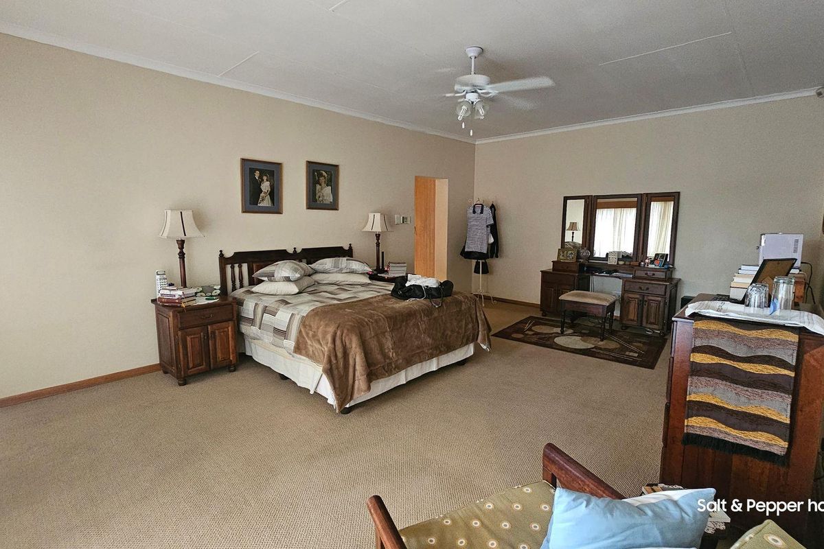 Spacious bedroom featuring neutral wall finishes, fitted carpeting, and a ceiling fan.