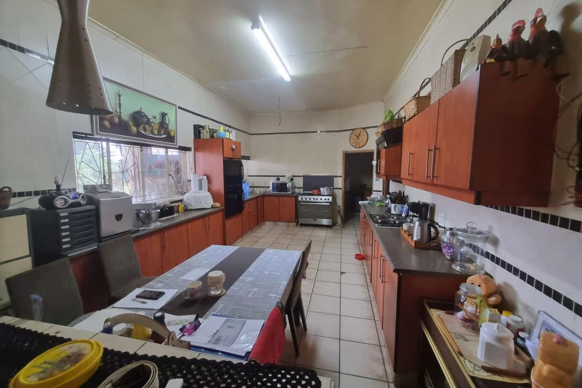 Spacious kitchen featuring extensive wooden cabinetry, tiled flooring, and a functional layout with integrated cooking appliances.