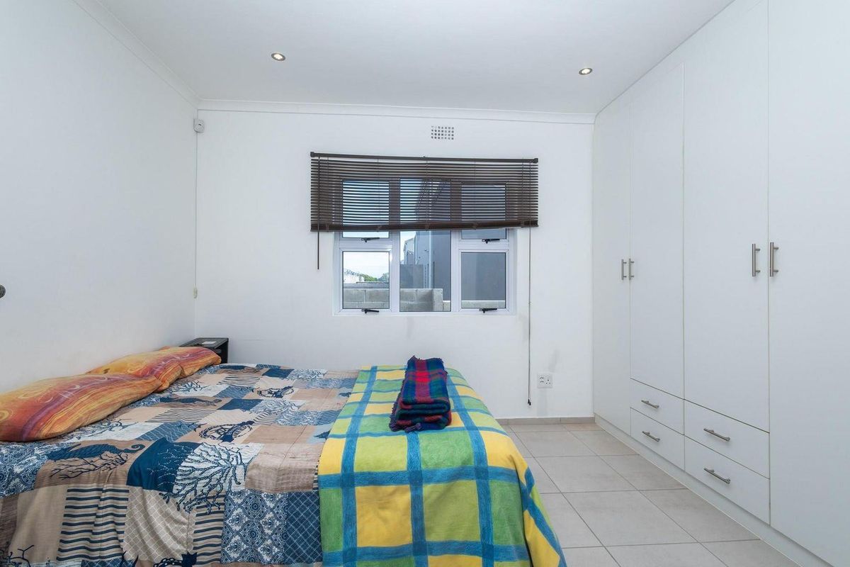 A bedroom featuring built-in cupboards, tiled flooring, and recessed ceiling lighting.