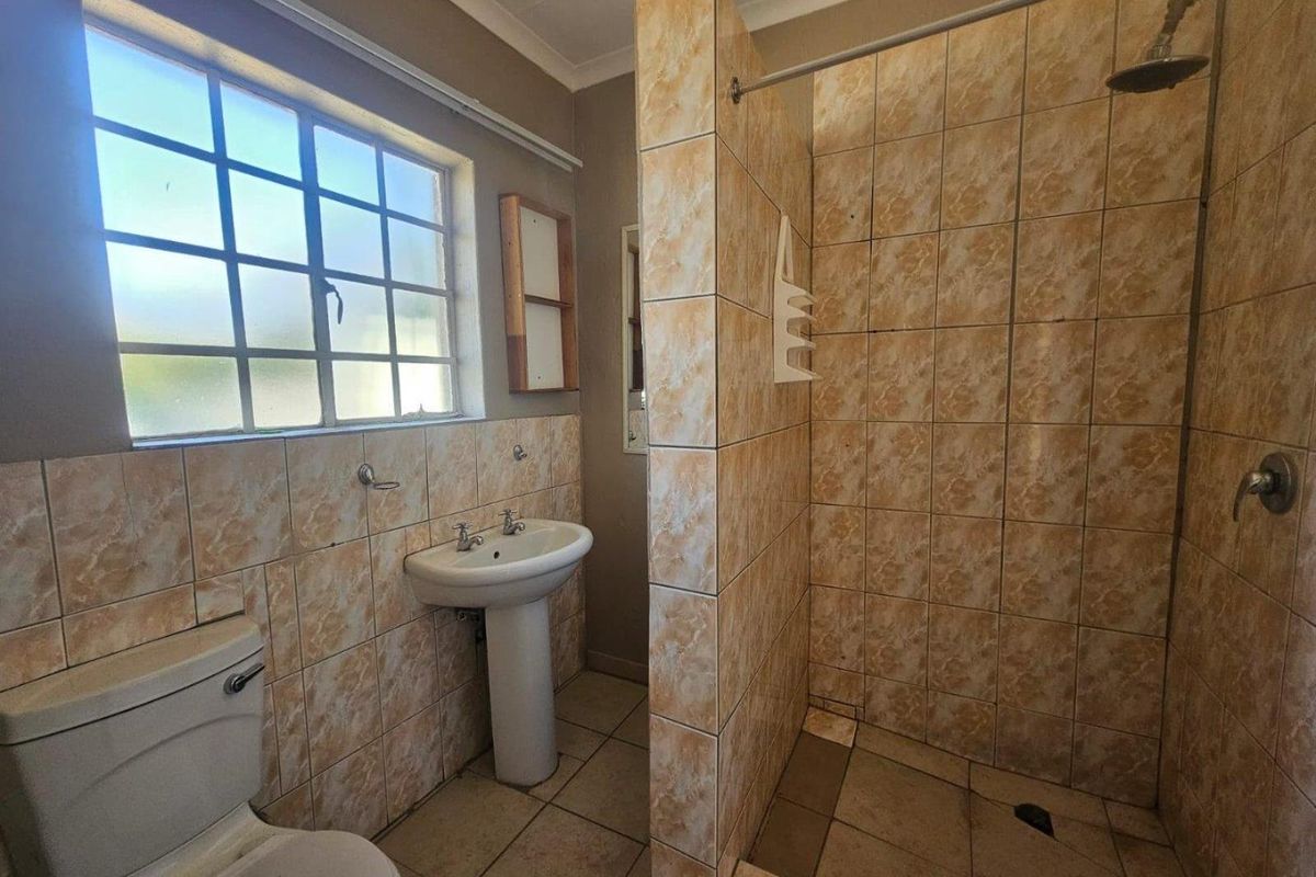 A functional bathroom featuring a pedestal basin, toilet, and a walk-in shower with tiled finishes throughout.