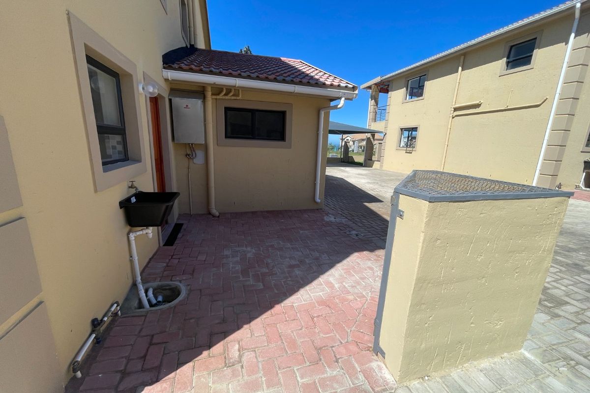 A paved rear courtyard area featuring a gas geyser, external utility sink, and access to the townhouse exterior.